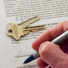 A person holding a pen and signing over a paper